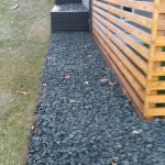 Rock bed beside a wood slat fence