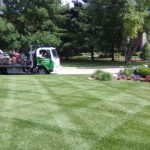 Striped lawn with a mowing crew's truck and trailer